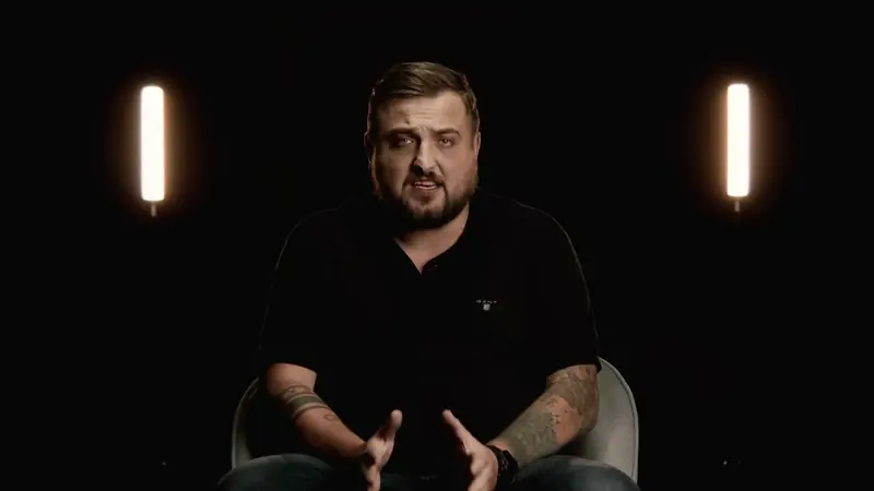 Wywiad — rozmówca na ciemnym tle między dwiema lampami